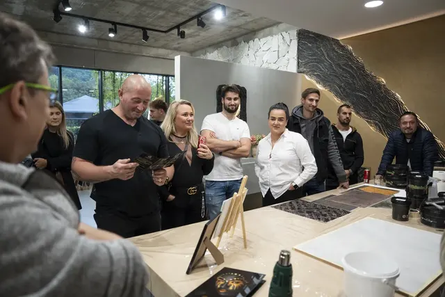 Ukázka dekorativních povrchů před zlato-černou reliéfní stěnou showroomu