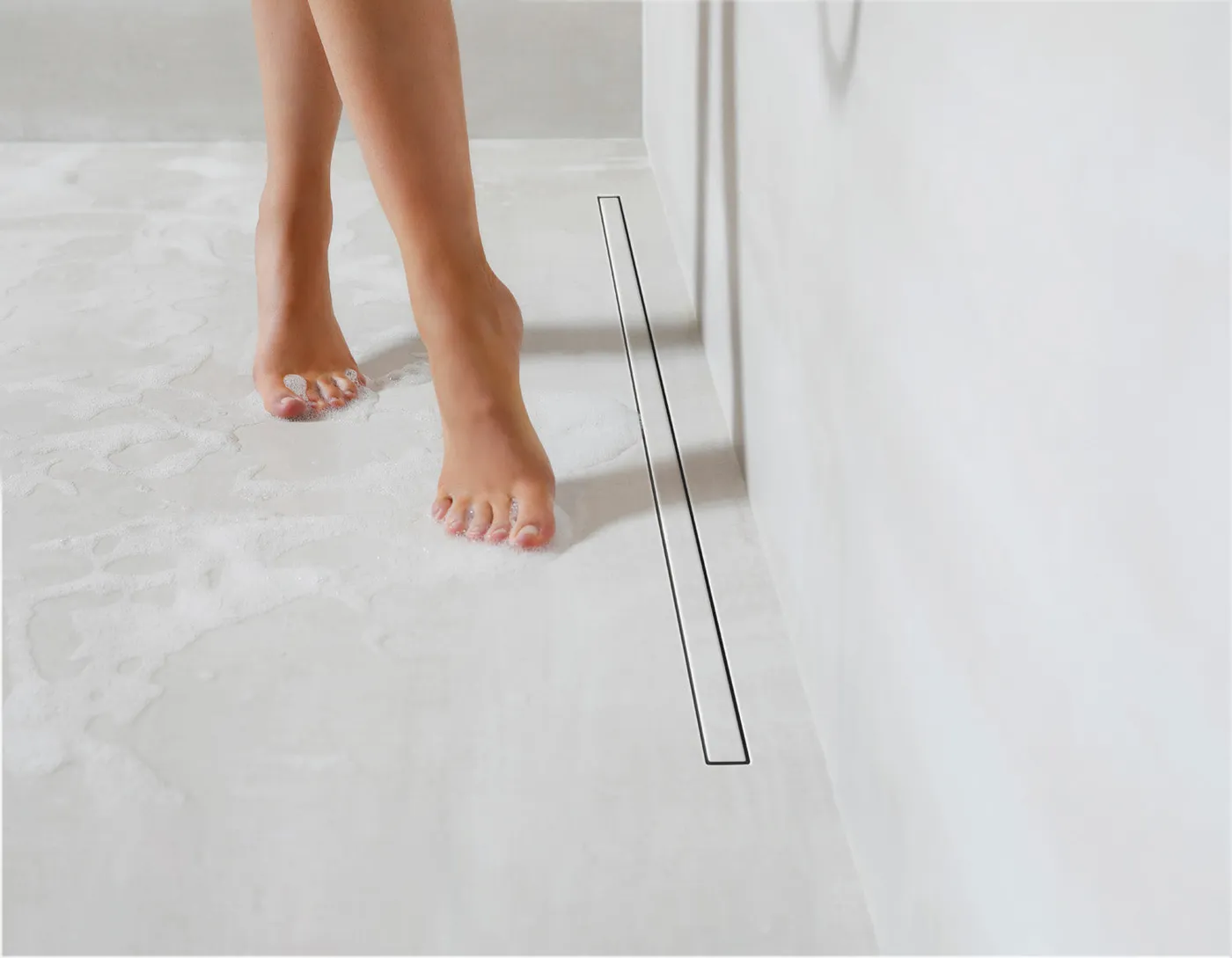 Bílý sprchový žlab Carrodrain Liquid zapuštěný v mikrocementové podlaze
